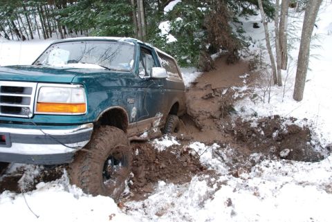 1996 Ford Bronco - A 1996 Ford Bronco is stuck in a muddy ditch with snow on the ground.