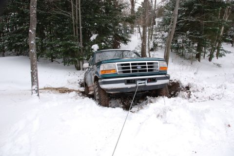 1996 Ford Bronco - 1996 Ford Bronco is stuck in the snow and mud, with a winch line attached to the front bumper.