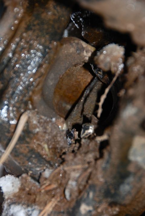 1996 Ford Bronco - This is a close-up of a rusty metal component, possibly from a vehicle, covered in dirt and debris.