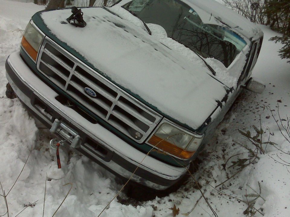 Green Ford Bronco stuck in snow, front view with winch