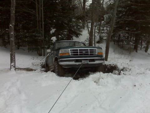 1996 Ford Bronco - A green Ford F-Series truck is stuck in deep snow and mud, with a winch line attached to the front.