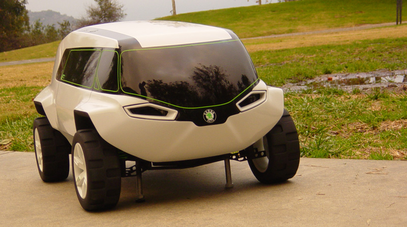 White concept car with green trim and large tires, parked on concrete