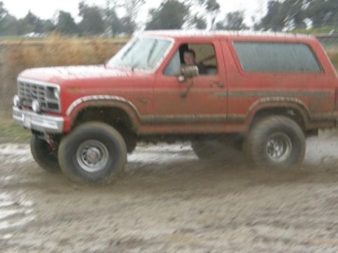 1986 Ford Bronco - This red Ford Bronco appears to be from the early 1980s, not 1986, as it navigates a muddy terrain.