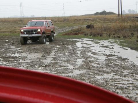 1986 Ford Bronco - Ford Bronco navigating a muddy off-road course on an overcast day.