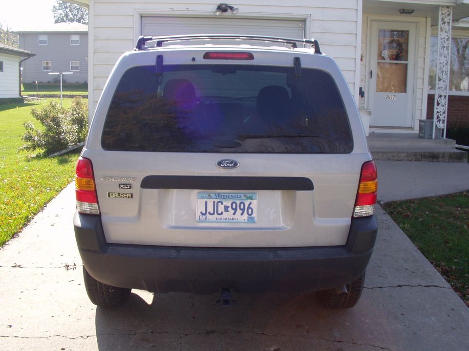 Silver Ford Escape XLT, direct rear view with Minnesota plate, parked in a residential driveway