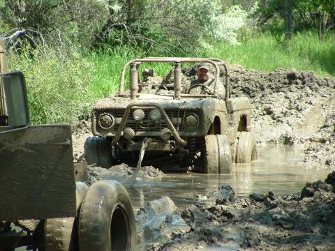 1992 Ford F-350 - Two off-road vehicles are stuck deep in mud and water, with one vehicle's front end prominently displayed.