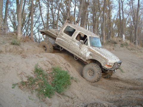 1992 Ford F-350 - This 1992 Ford F-350 is shown navigating a challenging sandy incline, covered in mud from off-road use.