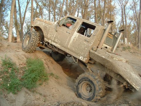 1992 Ford F-350 - This heavily modified pickup truck is navigating a challenging off-road course, covered in mud.