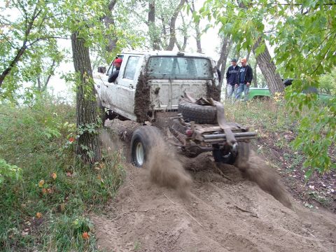 1992 Ford F-350 - A white 1992 Ford F-350 navigates a muddy trail, kicking up dirt as it goes.
