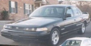 1998 Ford Crown Victoria - A dark-colored sedan is shown from a three-quarter front angle, with another vehicle partially visible in the foreground.
