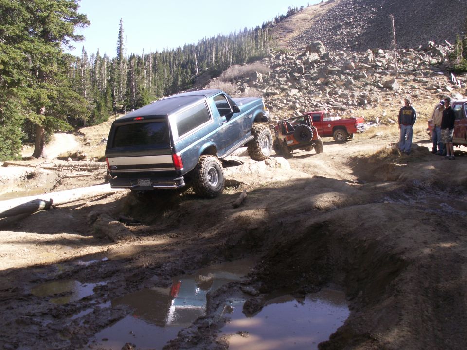 1986 Ford Bronco and other off-road vehicles navigating a muddy trail