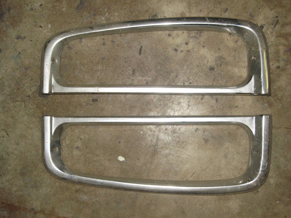 Pair of chrome headlight bezels on a concrete surface