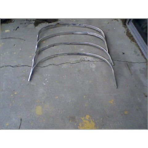1972 Ford Ranchero - Several curved chrome trim pieces are displayed on a concrete surface, suggesting they are automotive parts.