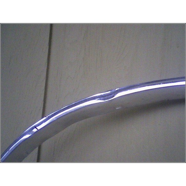 Curved chrome trim piece with a dent and scratch