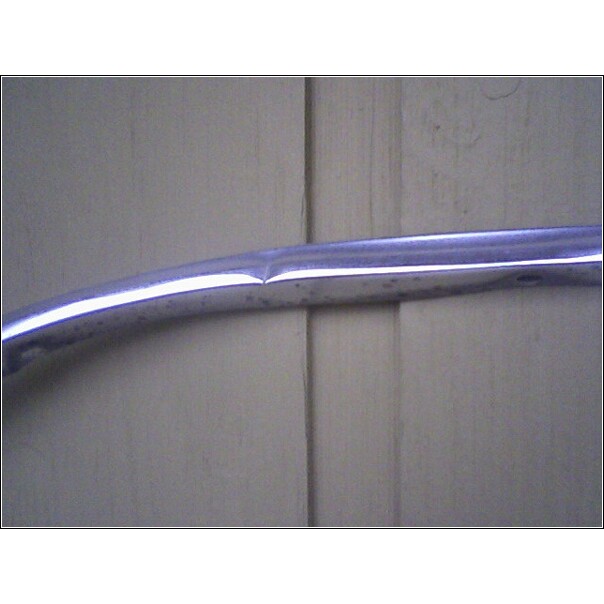 Chrome trim piece with a dent against a light-colored wall