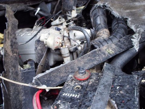 1995 Ford F-150 - Close-up of a damaged engine compartment showing internal components and wiring after an apparent accident.