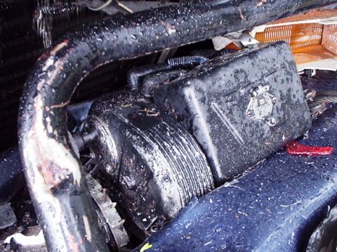 1995 Ford F-150 - Close-up view of a damaged engine compartment, showing a black box and hoses.
