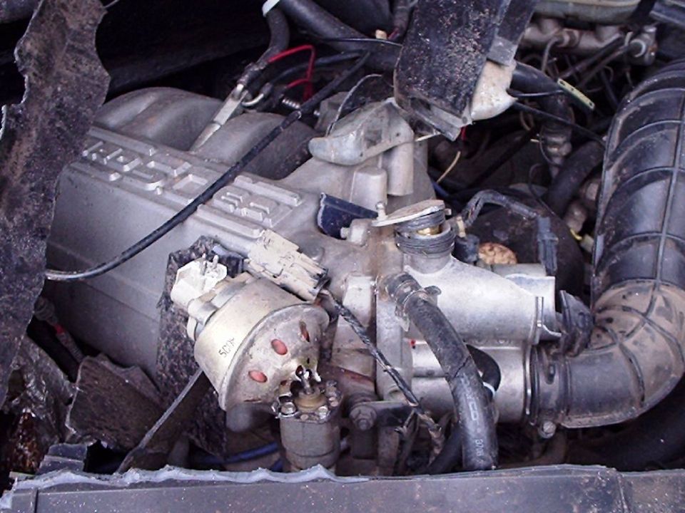 Close-up of a dirty engine bay with hoses and wiring visible. Text on intake reads '4.6L'