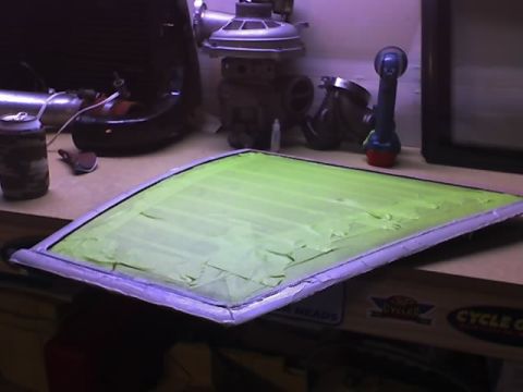 1991 Ford Mustang - A car window pane is covered with green masking tape, likely for repair or painting.