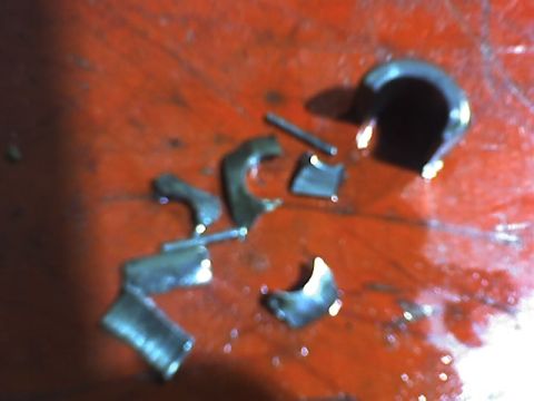 1991 Ford Mustang - Several broken metal engine components are scattered across a red surface, suggesting a mechanical failure.