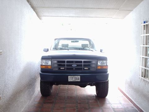 1995 Ford F-150 - Front view of a dark blue Ford F-150 truck parked in a garage, showing its grille and headlights.