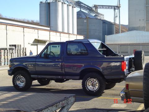 1995 Ford F-150 - A 1995 Ford F-150 is seen from the side, parked near industrial silos. A spare tire is mounted on the rear.