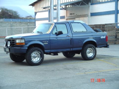 1995 Ford F-150 - This blue Ford Bronco, likely from the early 1990s, is viewed from the front-three-quarter angle.