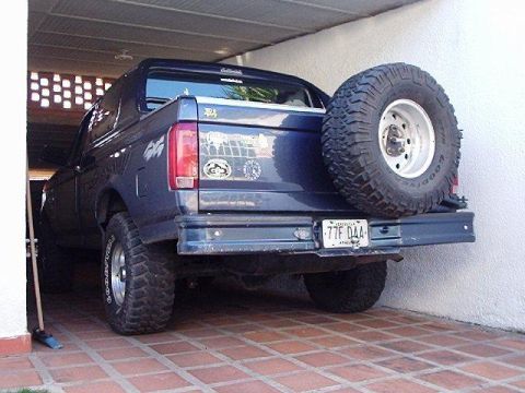 1995 Ford F-150 - Rear view of a dark blue Ford Bronco, showing its spare tire and license plate.