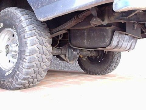 1995 Ford F-150 - The underside of a truck shows its rear axle, suspension, and fuel tank with large tires.