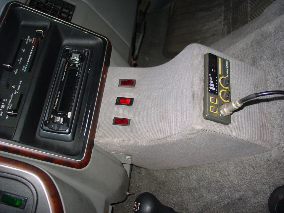 Gray carpeted custom console with Pioneer stereo, three red rocker switches, and a Cobra 19 CB radio in a truck interior
