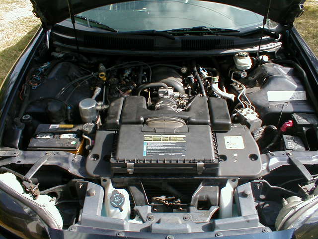 Engine bay of a dark car with plastic intake cover
