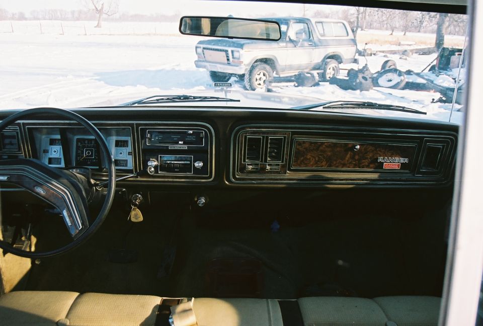 1979 Ford F-350 interior showing dashboard, steering wheel, and radio; another truck is visible outside