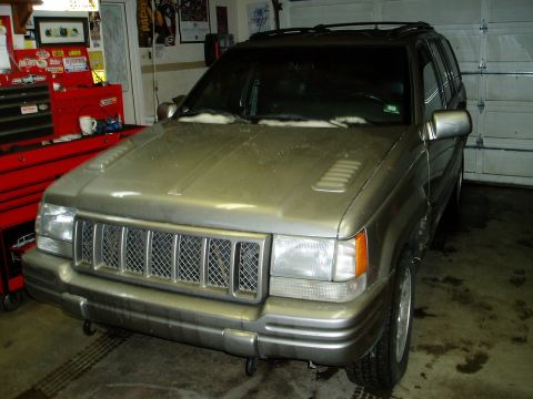 2000 Ford E350 - A silver Jeep Grand Cherokee is seen from the front-right in a garage setting.