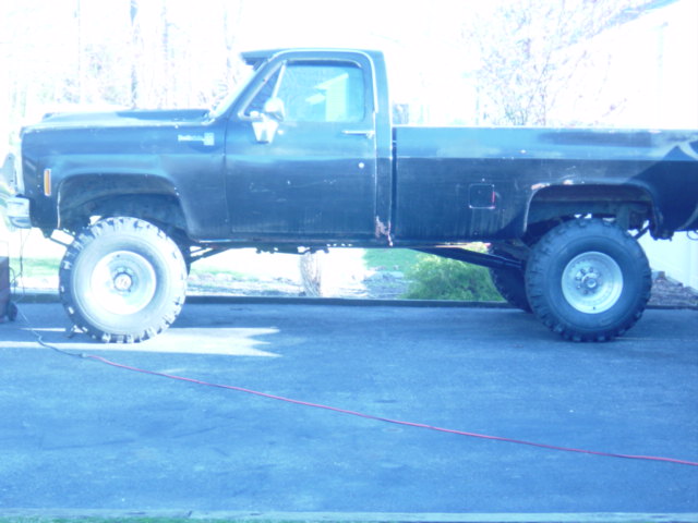 Black lifted pickup truck, side view, showing large tires and modified suspension