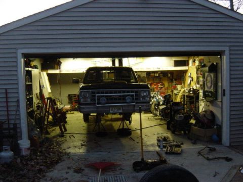1987 Suzuki Samurai - Pickup truck undergoing maintenance in a garage, raised on jack stands.