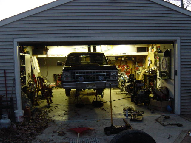 Black pickup truck on jack stands inside a garage, front view