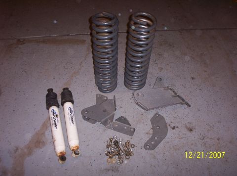 1995 Ford Bronco - A collection of suspension components, including shocks, springs, and brackets, laid out on a concrete floor.