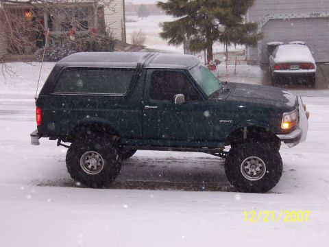 1994 Ford Bronco - A lifted dark green 1992 Ford Bronco sits in the snow, with another car visible in the background.