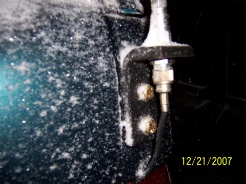 1994 Ford Bronco - Close-up of a snow-covered antenna mount on the side of a dark green vehicle.