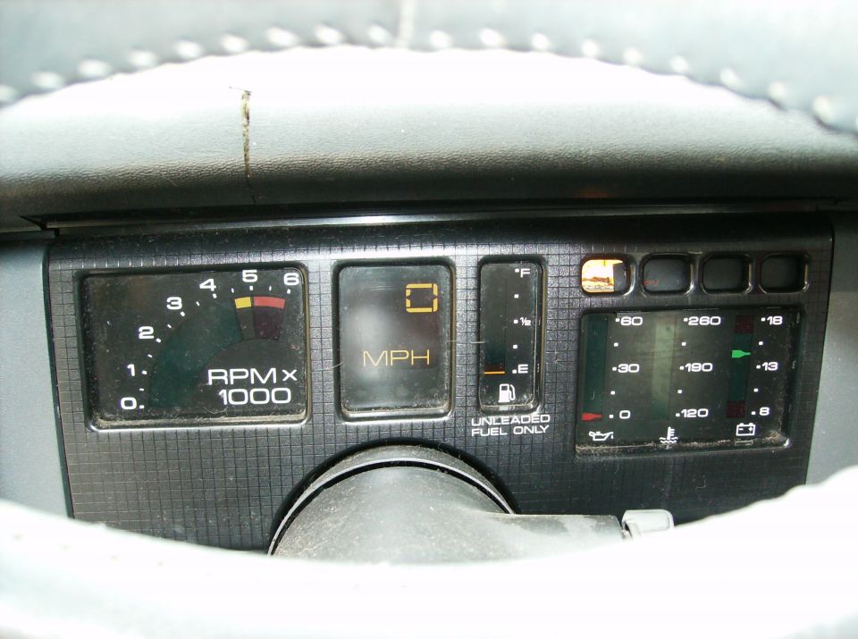 Car dashboard with tachometer, digital speedometer, fuel gauge, temperature gauge, oil pressure gauge, and battery indicator
