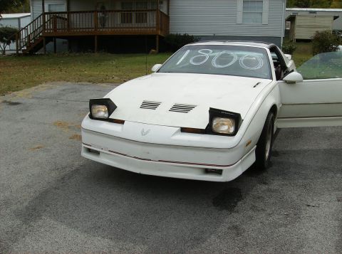 1995 Ford Probe - White 1990 Pontiac Firebird is shown from the front with its pop-up headlights down and '1800' written on the windshield.