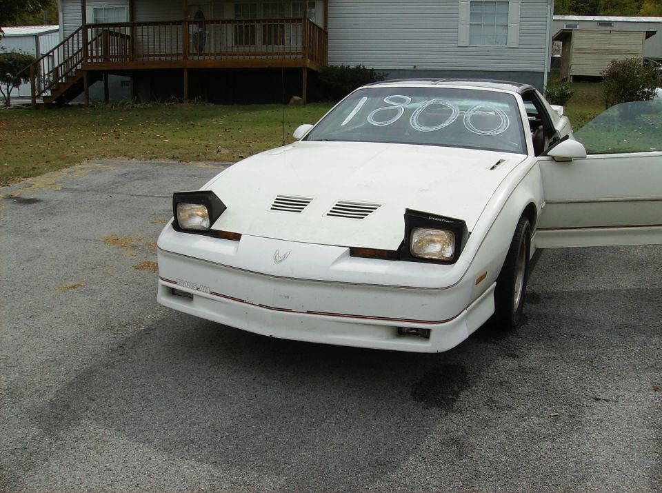 White 1990 Pontiac Firebird front view with pop-up headlights and '1800' written on windshield