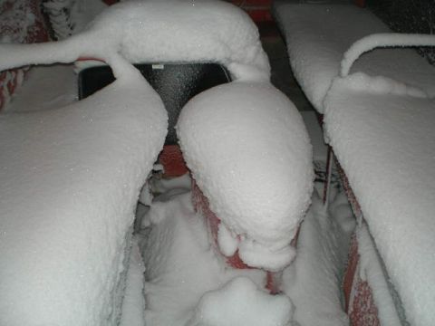 2000 Ford E350 - Several vehicles are completely covered in thick snow, making identification impossible.