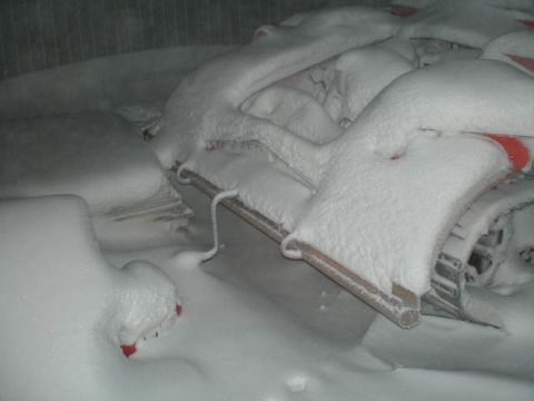 2000 Ford E350 - Parts of a vehicle are buried under a thick layer of snow, with some red elements peeking through.