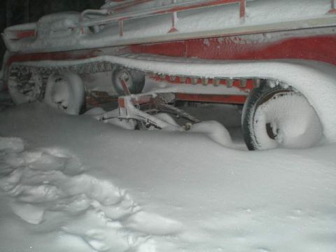 2000 Ford E350 - A vehicle, possibly a snowcat, is partially buried in deep snow, showing its tracks and wheels.