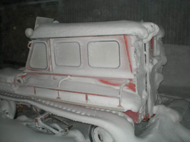 Side view of a snow-covered tracked vehicle with red accents