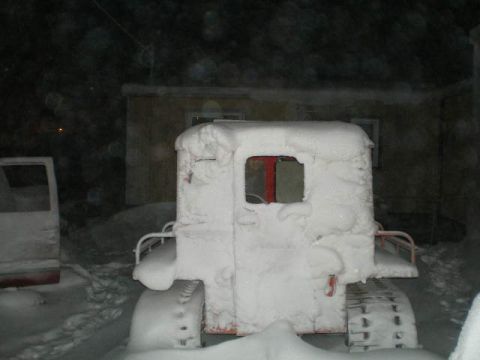 2000 Ford E350 - A tracked vehicle covered in snow sits next to another vehicle during a snowfall.