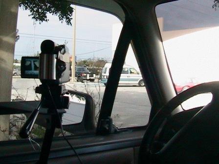 1996 Ford Bronco - A video camera is set up on a tripod inside a vehicle, capturing the scene outside.