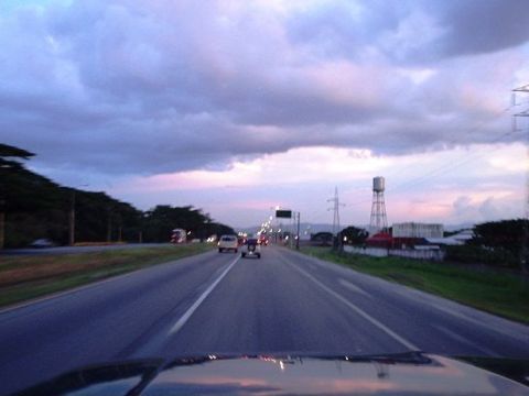 1995 Ford F-150 - A highway scene unfolds under a dramatic twilight sky, with vehicles traveling and a water tower visible in the distance.