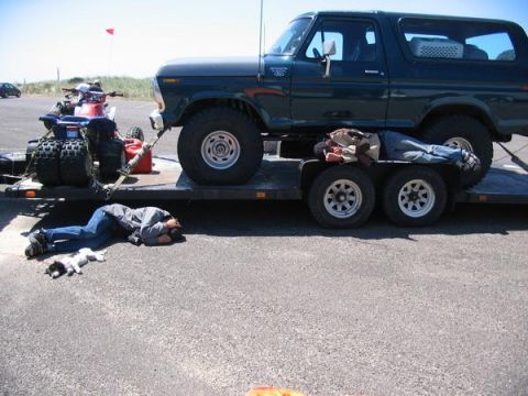 1979 Ford Bronco - A dark green 1978 Ford Bronco is transported on a trailer, accompanied by an ATV and two individuals resting individuals.